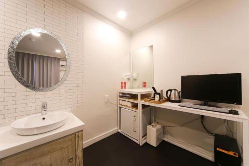uma casa de banho branca com um lavatório e um espelho em Prince Motel em Busan