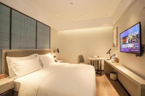 a bedroom with a white bed and a tv at Ji Hotel Xiamen Railway Station North Square in Jiangtouzhen