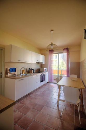 une cuisine avec des armoires blanches et une table avec des chaises dans l'établissement Appartement Cours Général Leclerc AJACCIO, à Ajaccio