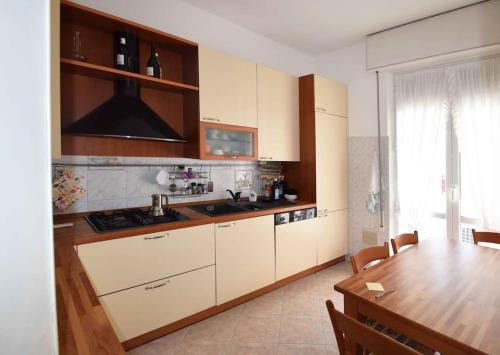 une cuisine avec des placards blancs et une table en bois dans l'établissement Ampio appartamento 8 POSTI LETTO, à Rapallo