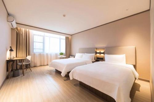 a hotel room with two beds and a desk at Hanting Hotel Suqian Powerlong Plaza in Suqian