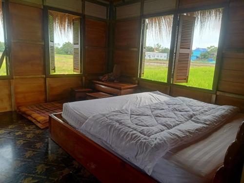 a bedroom with a large bed in a room with windows at Meta Homestay in Phumĭ Puŏk Chăs