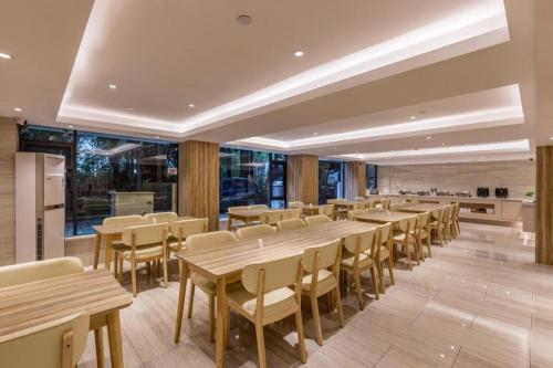 a dining room with wooden tables and chairs at Hanting Premium Hotel Xiamen SM Plaza Songbo in Jiangtouzhen