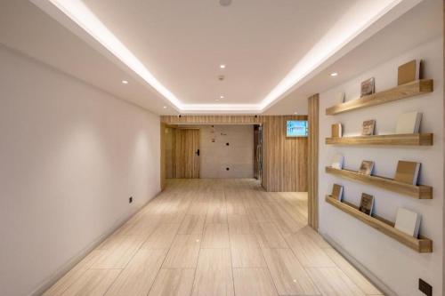 un pasillo con paredes blancas, suelos de madera y estanterías en Hanting Premium Hotel Xiamen SM Plaza Songbo en Jiangtou