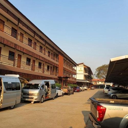 un parking avec des voitures garées devant un bâtiment dans l'établissement S Residence (S HOTEL), à Ban Nong Pla Kho