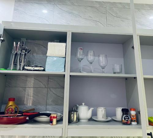 a white cabinet with wine glasses and dishes in it at Entire Furnished Apartment Unit in Kira in Kira