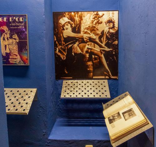 a museum display with paintings andartifacts on a blue wall at Hotel Utopía in Benalup Casas Viejas