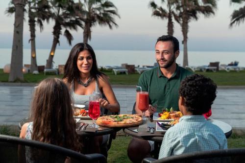 een groep mensen die rond een tafel pizza eten bij Grand Ocean Sokhna Hotel in Ain Sokhna