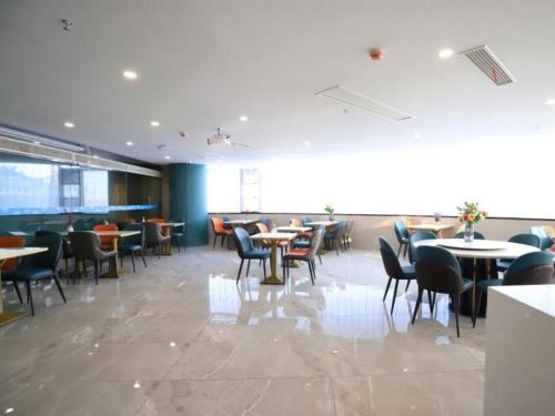 a restaurant with tables and chairs in a room at VX Hotel Jiangsu Taizhou Xinghua RT-Mart in Xinghua