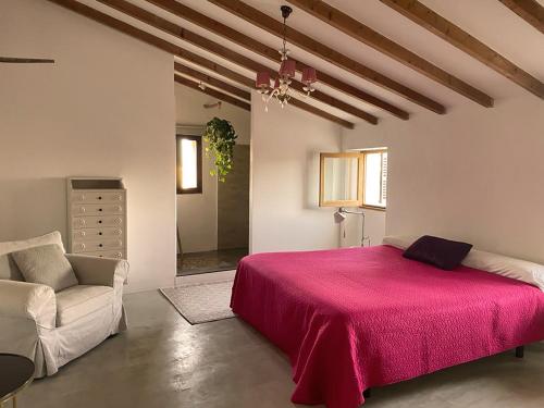 a bedroom with a pink bed and a chair at Casa Mona Turismo de Interior in Llubí