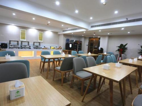 um restaurante com mesas e cadeiras num quarto em GreenTree Inn Luoyang Railway Station Wangfujing Wangcheng Park em Luoyang