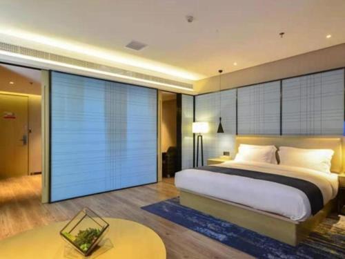 a bedroom with a large bed and a large window at VX Hotel Hubei Wuhan Moshui Lake National Expo Yongwang in Han-yang-hsien