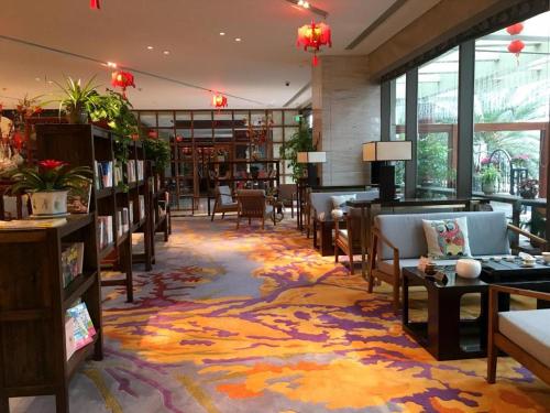a library with chairs and tables and bookshelves at Balan International Hotel in Dujiangyan