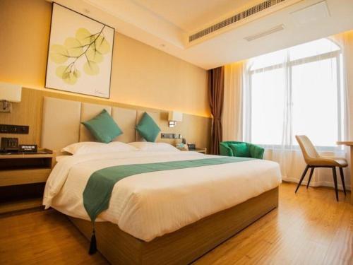 Pokój hotelowy z dużym łóżkiem z zielonymi poduszkami w obiekcie GreenTree Inn Jumang Plaza w mieście Mangshi
