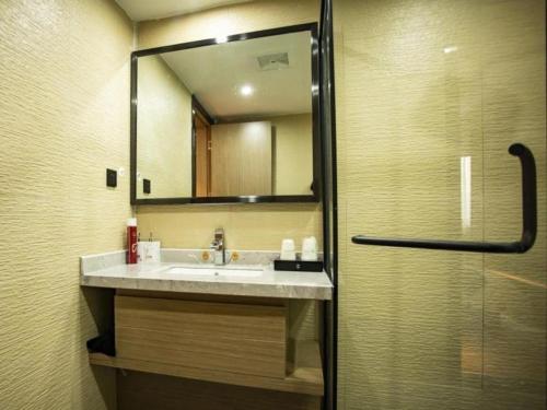 W łazience znajduje się umywalka i lustro. w obiekcie GreenTree Inn Jumang Plaza w mieście Mangshi
