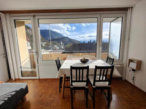 une salle à manger avec une table, des chaises et une grande fenêtre dans l'établissement 2 bedroom Apartment at Bahnhofcity, à Feldkirch