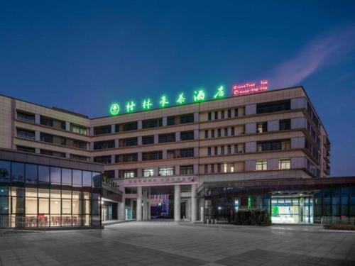 a building with a green sign on top of it at GreenTree Inn Jiangsu Yancheng High-Tech Pioneer Park in Yancheng