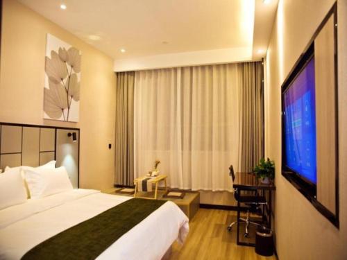 a hotel room with a bed and a flat screen tv at GreenTree Inn Xinjiang Kashgar Food Street in Kashgar