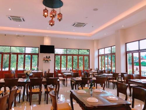 a restaurant with tables and chairs and windows at KOKHABURI HOTEL in Ban Chomphu