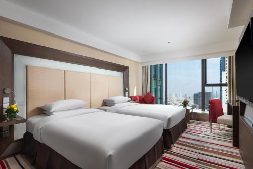 a row of beds in a hotel room with a window at Novotel Nanjing Central in Nanjing