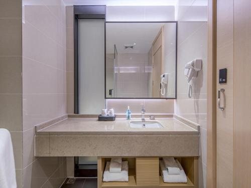 a bathroom with a sink and a mirror at City Comfort Inn Wuzhou Xijiang Thrid Bridge in Cangwu