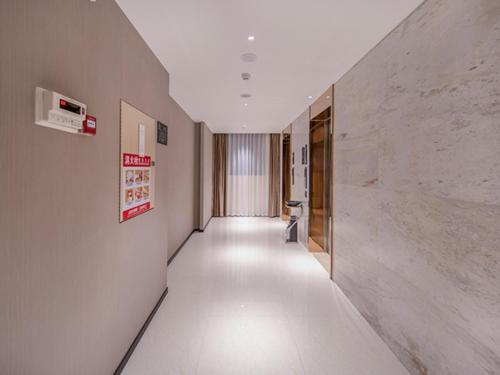 un largo pasillo con suelos blancos y una pared blanca en City Comfort Inn Wuzhou Xijiang Thrid Bridge, en Cangwu
