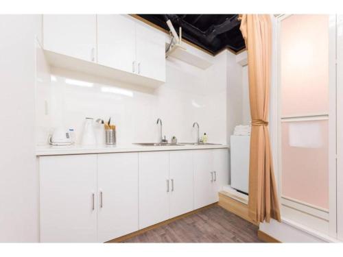 a white kitchen with a sink and a refrigerator at Tora Hotel Rikugien in Tokyo