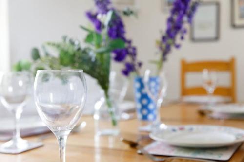 a table with two wine glasses and a vase of flowers at 3bd Family Beach Retreat in West Wittering in West Wittering