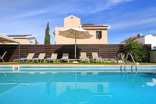 een zwembad met stoelen en een parasol naast een huis bij Villa Summer in Protaras