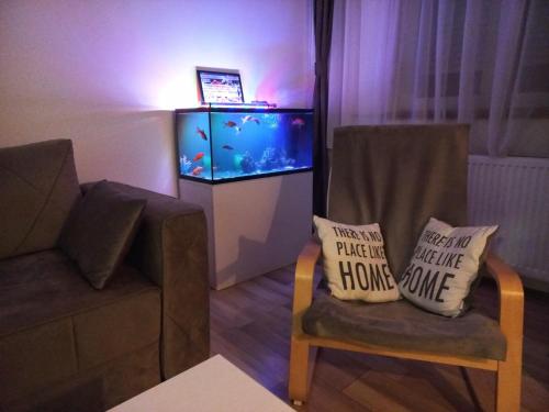a living room with a fish tank and a chair with two pillows at TOP Apartman in Šabac