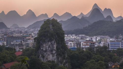 a mountain in front of a city with mountains at Borrman Hotel Guilin Elephant Hill Park Li Lake in Guilin