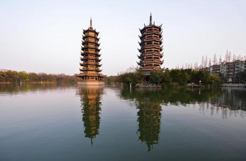 two towers sitting on top of a body of water at Borrman Hotel Guilin Elephant Hill Park Li Lake in Guilin