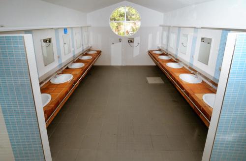 uma casa de banho com uma fila de lavatórios e espelhos em Kampaoh El Puerto de Santa María em El Puerto de Santa Maria