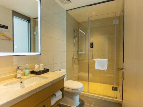 a bathroom with a shower and a toilet and a sink at City Comfort Inn Shaoguan Biguiyuan Phoenix City Gold Village in Shaoguan