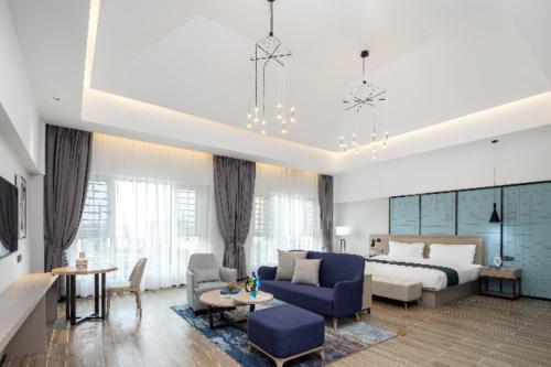 uma sala de estar com uma cama e um sofá azul em Echarm Hotel Haikou Yehai Avenue Airport em Lingshan
