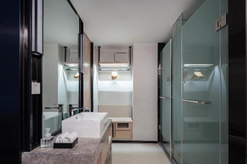 uma casa de banho com um lavatório e uma cabina de duche em vidro. em Echarm Hotel Haikou Yehai Avenue Airport em Lingshan