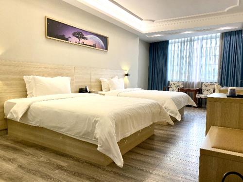 a hotel room with two beds and a table at JTOUR Inn Maoming Huazhou Beijing Road Railway Station in Sanguantang
