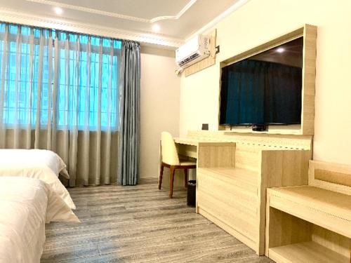 a hotel room with a bed and a tv and a desk at JTOUR Inn Maoming Huazhou Beijing Road Railway Station in Sanguantang
