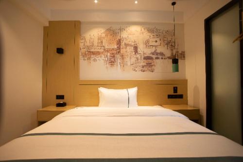 懷化的住宿－City Comfort Inn Huaihua East Station，卧室配有一张白色床,墙上挂有绘画作品