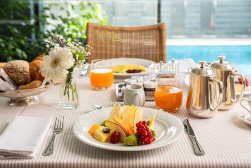 a table with a plate of food and fruit on it at Hotel Excelsior in Marina di Massa