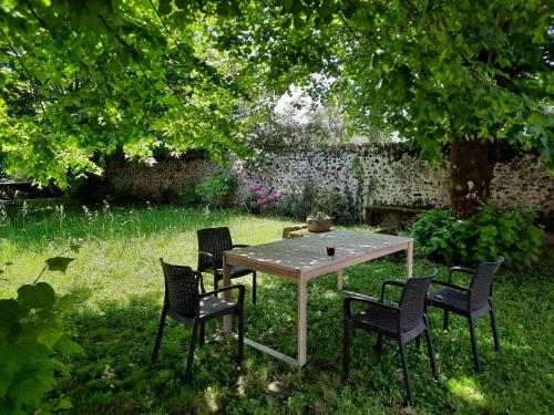 une table et des chaises dans une cour avec un arbre dans l'établissement Le Presbytère des Renards, à Magnac-Laval