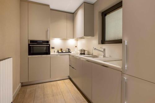 a kitchen with white cabinets and a sink and a window at Tzl Suites Hotel Nişantaşı in Istanbul