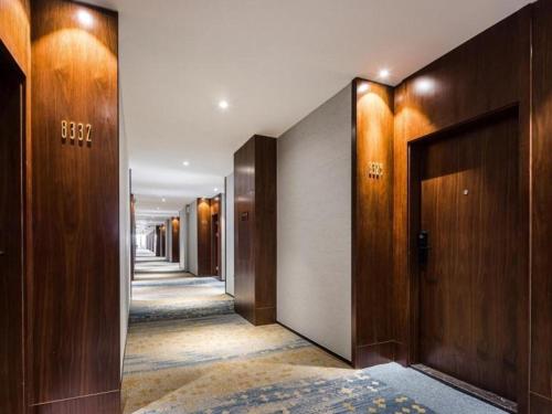 un couloir avec des portes en bois et un couloir avec de la moquette dans l'établissement GEM Hotel Changzhou Xuejia'aoyuan North High-Speed Railway Station, à Xiaoxinqiao