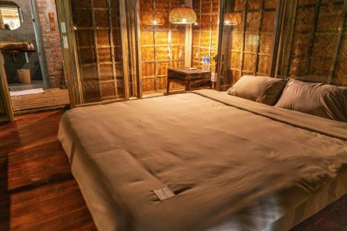uma cama grande num quarto com pisos em madeira em Dinh Gia Trang - Homestay & Coffee em Thế Rương