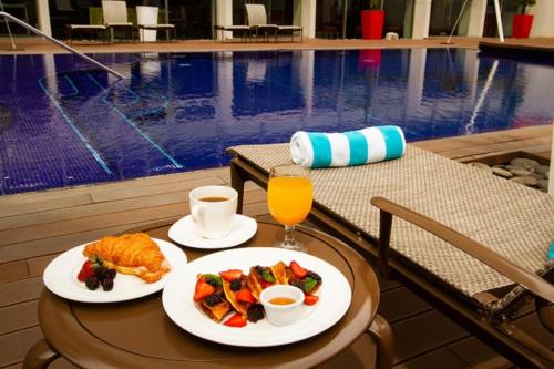 uma mesa com dois pratos de comida ao lado de uma piscina em ADRIATIKA Hotel Boutique Guatemala - Adults Only em La Aurora