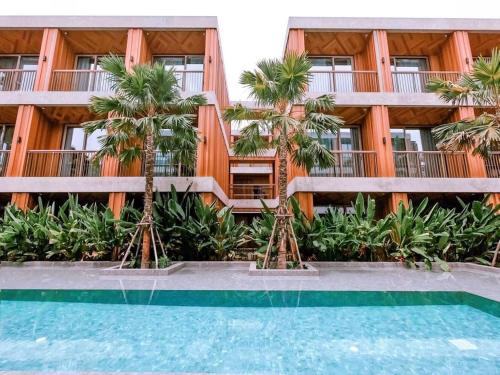 un edificio con palmeras frente a una piscina en Riverton Hotel en Samut Songkhram