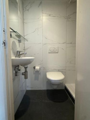 a white bathroom with a toilet and a sink at Hello Noordwijk - Zomerhuis Quarles van Uffordstraat 89 in Noordwijk