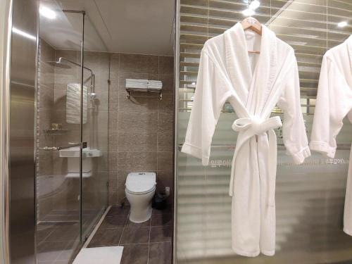 a bathroom with a toilet and a robe on a rack at jeju illua hotel in Jeju
