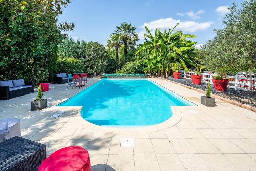 een zwembad met blauw water in een achtertuin bij Carré Pau Airport Hôtel in Serres-Castet