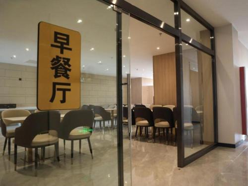 a dining room with chairs and tables and a sign at Green Tree Inn Express Inner Mongolia Ulan Qab High-Speed Railway Station in Ulanqab